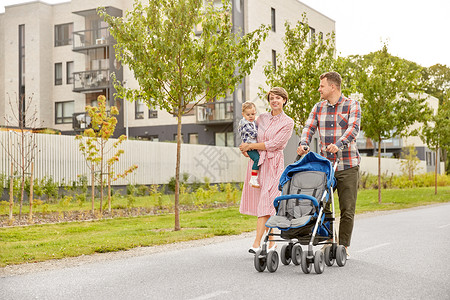 扁平婴儿车家庭父母带着婴儿婴儿车沿着城市行走背景