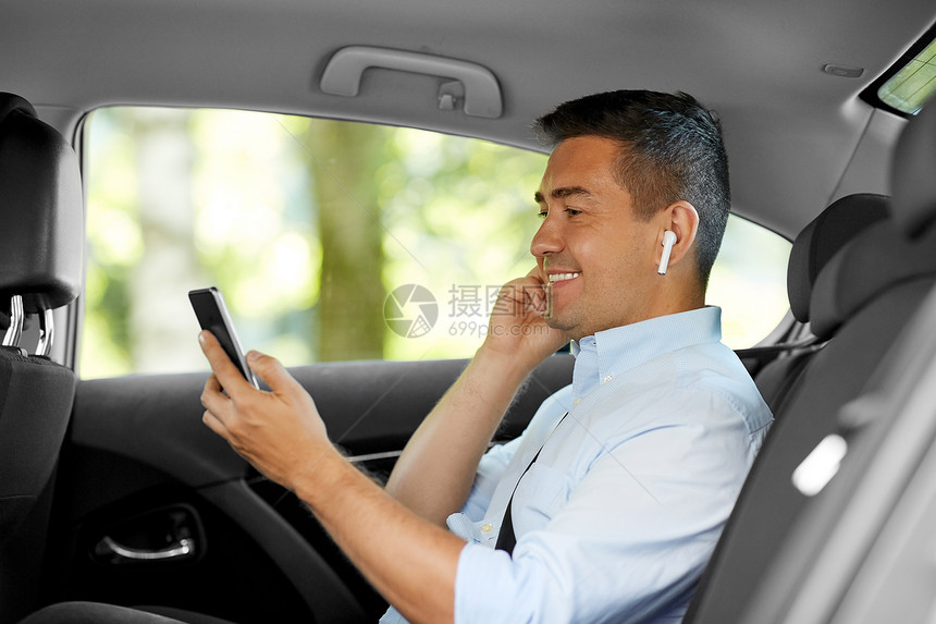 运输,商业技术微笑的男乘客商人与无线耳机用智能手机出租车后座出租车上耳机手机的乘客图片