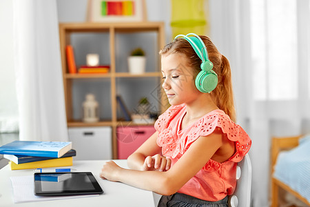 儿童,教育技术学生女孩耳机与平板电脑家庭办公桌女孩戴着耳机,家里平板电脑图片