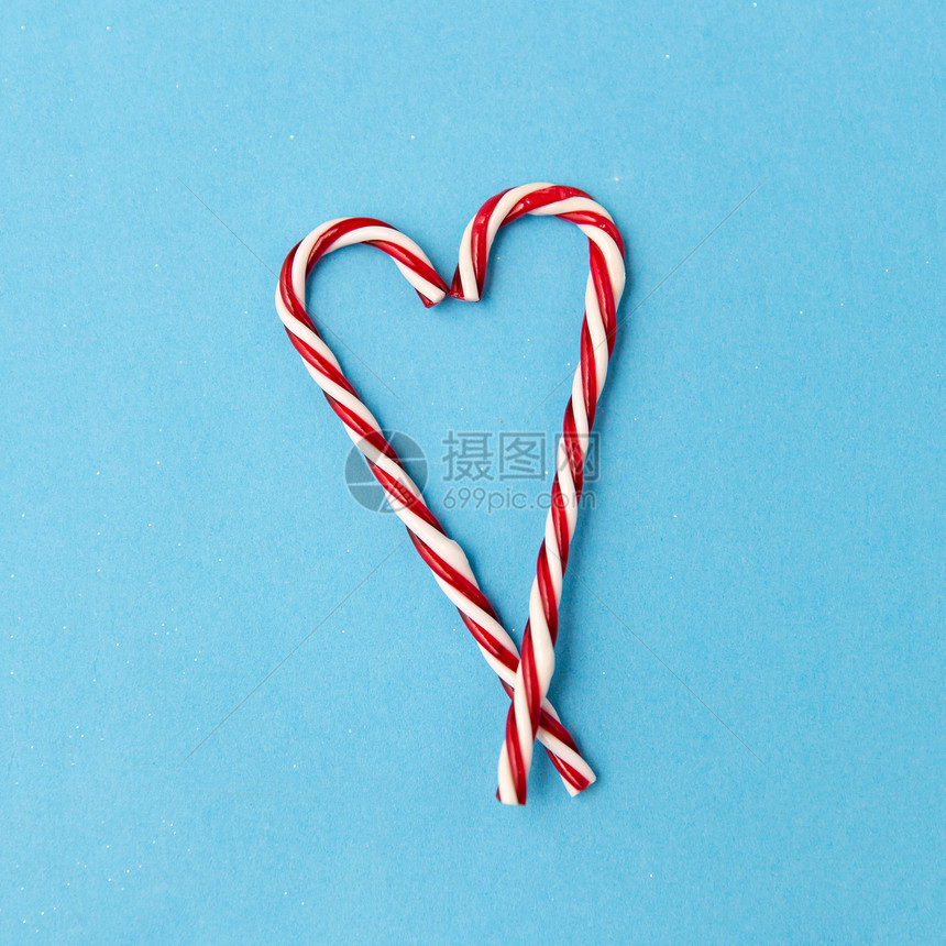 诞节寒假的糖果甘蔗装饰形状的心蓝色背景糖果手杖装饰的形状的心图片