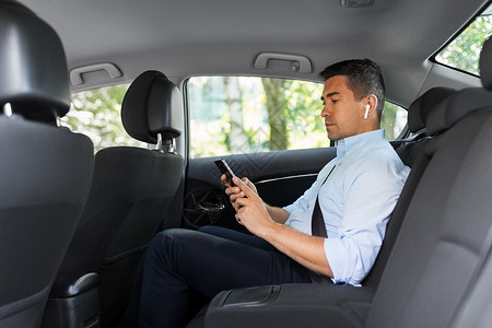 夸张听电话运输,商业技术男乘客商人用无线耳机用智能手机出租车后座出租车上耳机手机的乘客设计图片