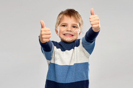 童,手势人的微笑的小男孩条纹套头衫拇指灰色背景穿条纹套衫的小男孩竖大拇指背景图片
