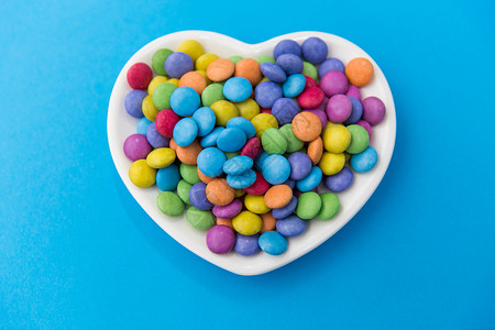 糖果,糖果情人节糖果滴心形盘子上的蓝色背景蓝色背景上心形盘子上的糖果图片
