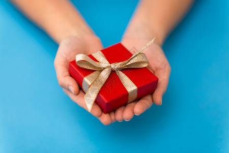 节日,礼物问候手小诞红色礼品盒与金结蓝色背景双手捧着红色的小诞礼盒图片