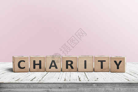 慈善标志个木制桌子上,背景粉红色的墙社会的高清图片素材