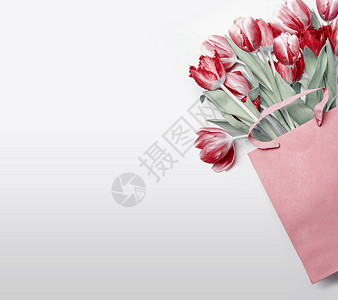 浅灰色背景下纸质购物袋中的红色郁金香节日的春天花花礼物作曲春季假期,问候销售为您的背景图片