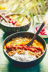 冰沙芒果碗与奇亚种子,酸奶布丁蔓越莓,坚果,燕麦片顶部椰子壳与勺子,顶部视图健康干净的早餐美味的节食夏季食物背景图片