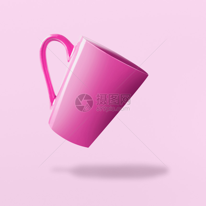 粉红色背景下飞粉红色的空杯图片
