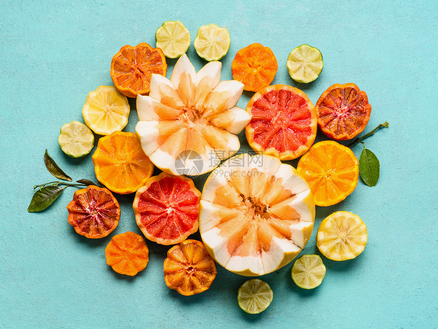 各种柑橘类水果浅蓝色背景,顶部视野与半的橙色水果,柠檬,柚子,橘子,石灰,柚子血橙成平躺健康的食物图片