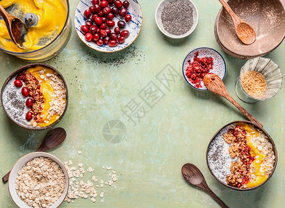 健康的冰沙碗背景早餐芒果冰沙碗准备椰子壳与顶部燕麦片,辣椒种子,浆果坚果夏季健康饮食的风景背景图片