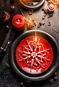 诞餐桌红色黑色盘子,装饰雪花,燃烧蜡烛仙女灯黑暗的背景的风景图片