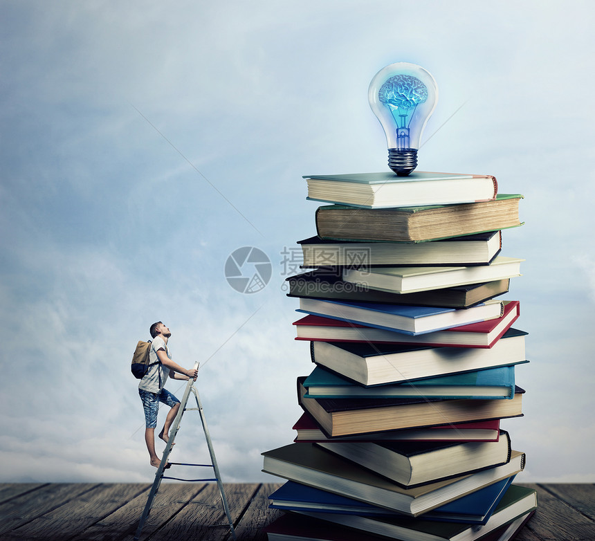 梯子上的小男孩,背上个袋子,试图爬上堆书寻找灯泡寻找知识的图片