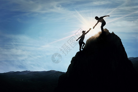 两个男孩攀爬个岩石危险的悬崖时伸出援手的剪影友好的手高山远足鼓舞人心的队合作,信念支持的象征背景
