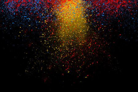 黑色爆炸碎片冻结运动的彩色粉末下来黑暗黑色背景黄色蓝色红色灰尘的抽象粒子云壁纸背景