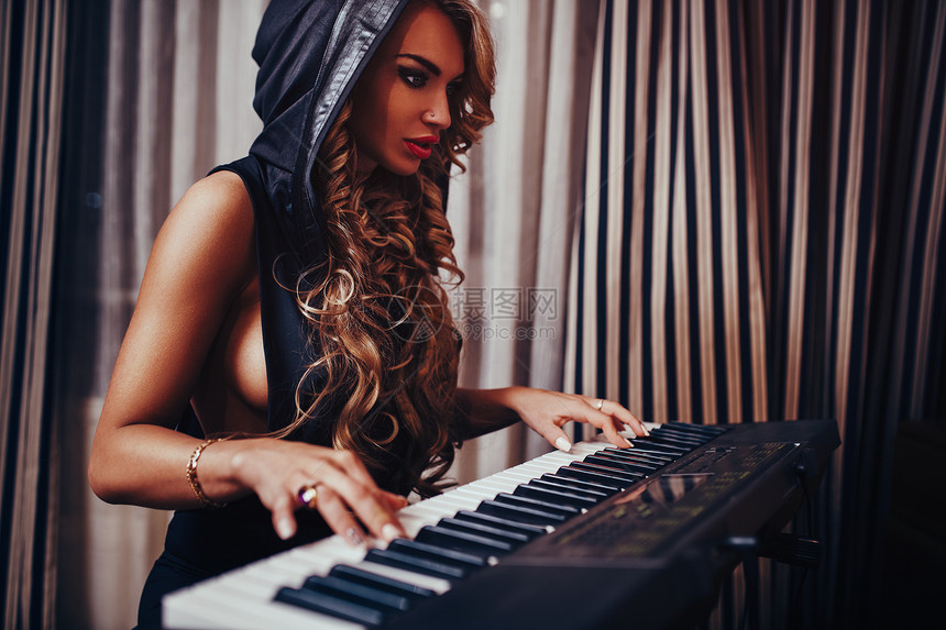 轻女子音乐家感时尚肖像夜间室内弹钢琴女音乐家肖像图片