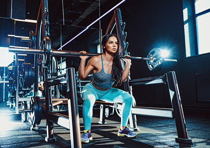 轻的运动感的黑发女人穿着蓝色的衣服,重量的仰卧坐体育女子训练图片