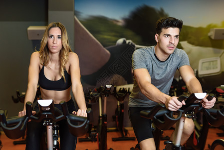两个人健身房骑自行车,锻炼腿,氧运动,骑自行车夫妇课上穿着运动服图片