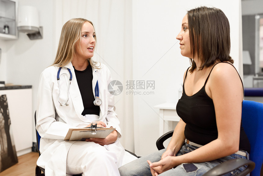 女医生向她的病人解释诊断黑发女人医疗办公室金发女孩协商图片