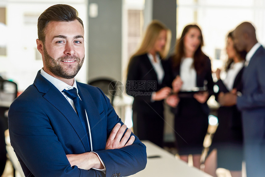 高加索商人领袖现代办公室里看着相机,多民族的商人后台工作队合作的留着胡子的轻人穿着蓝色的西装图片