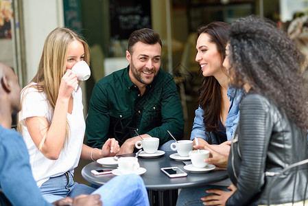 孤单对影成三人五个朋友成的多种族小喝咖啡三个女人两个男人咖啡馆,聊天,笑,享受他们的时间生活方式友谊与真人模特背景