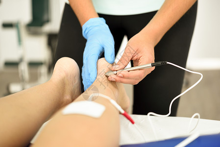 电针干针连接机,针灸师用于女患者针刺,由EPI内经皮电钻引导理疗中心名轻女子踝关节物理治疗中的电刺激物理疗法高清图片素材