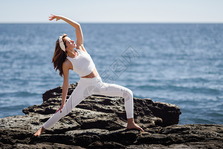 海滩上瑜伽的轻女子女运动员身穿白色运动服,太阳下与海的背景人物背景图片