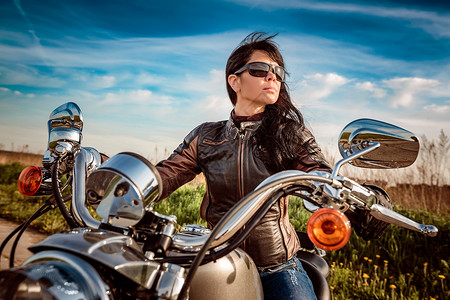 骑自行车的女孩穿着皮夹克太阳镜坐摩托车上背景图片