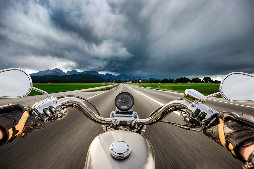 骑摩托车的自行车场闪电风暴中沿着道路飞驰福根塞施旺瑙,德国巴伐利亚图片