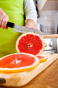 女人的手厨房里切新鲜的柚子图片