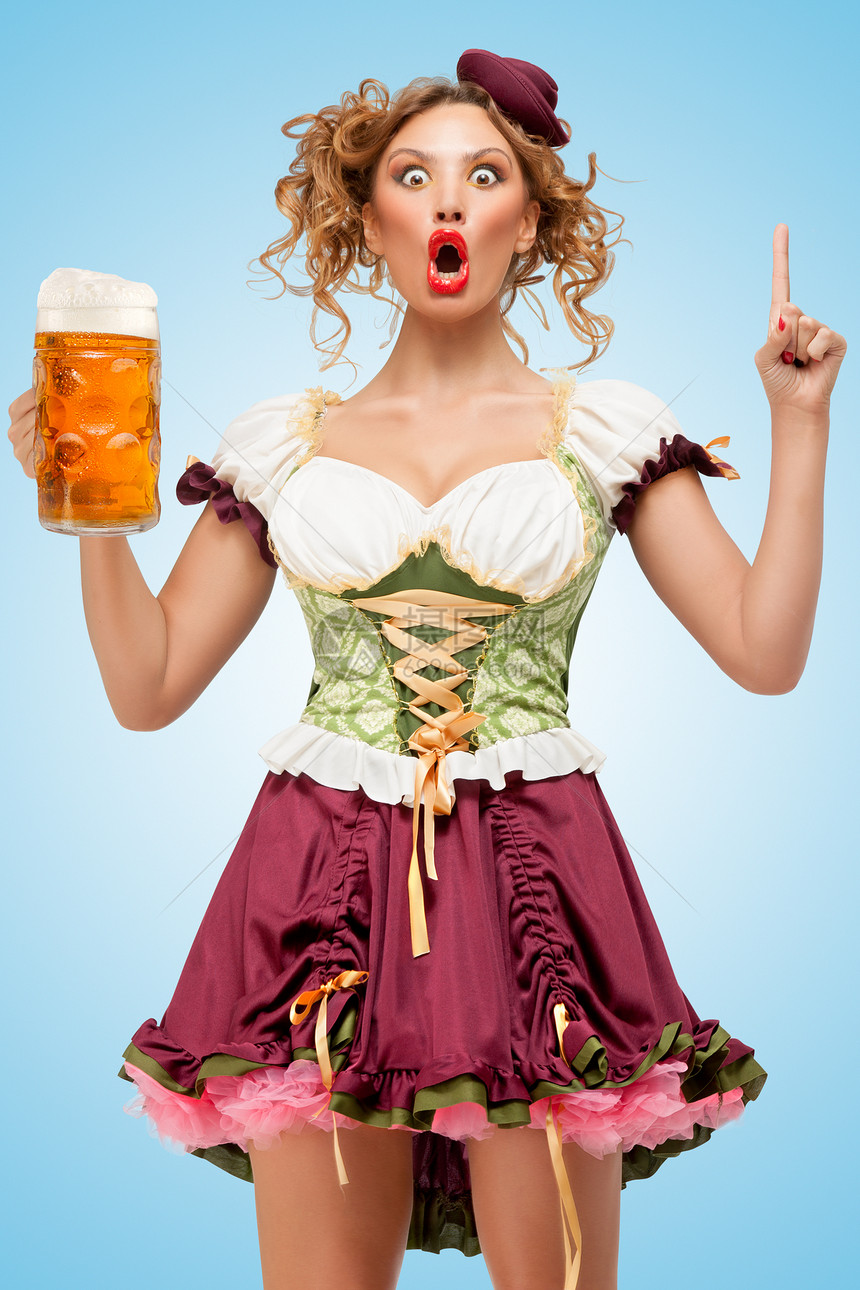 轻感的啤酒节女服务员穿着传统的巴伐利亚连衣裙,戴着个啤酒杯,蓝色背景上个想法图片