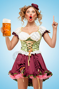 轻感的啤酒节女服务员穿着传统的巴伐利亚连衣裙,戴着个啤酒杯,蓝色背景上个想法主意高清图片素材