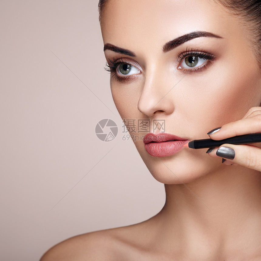 美丽的女人用口红涂嘴唇漂亮的女人脸化妆细节完美皮肤的美容模特红唇指甲修剪图片