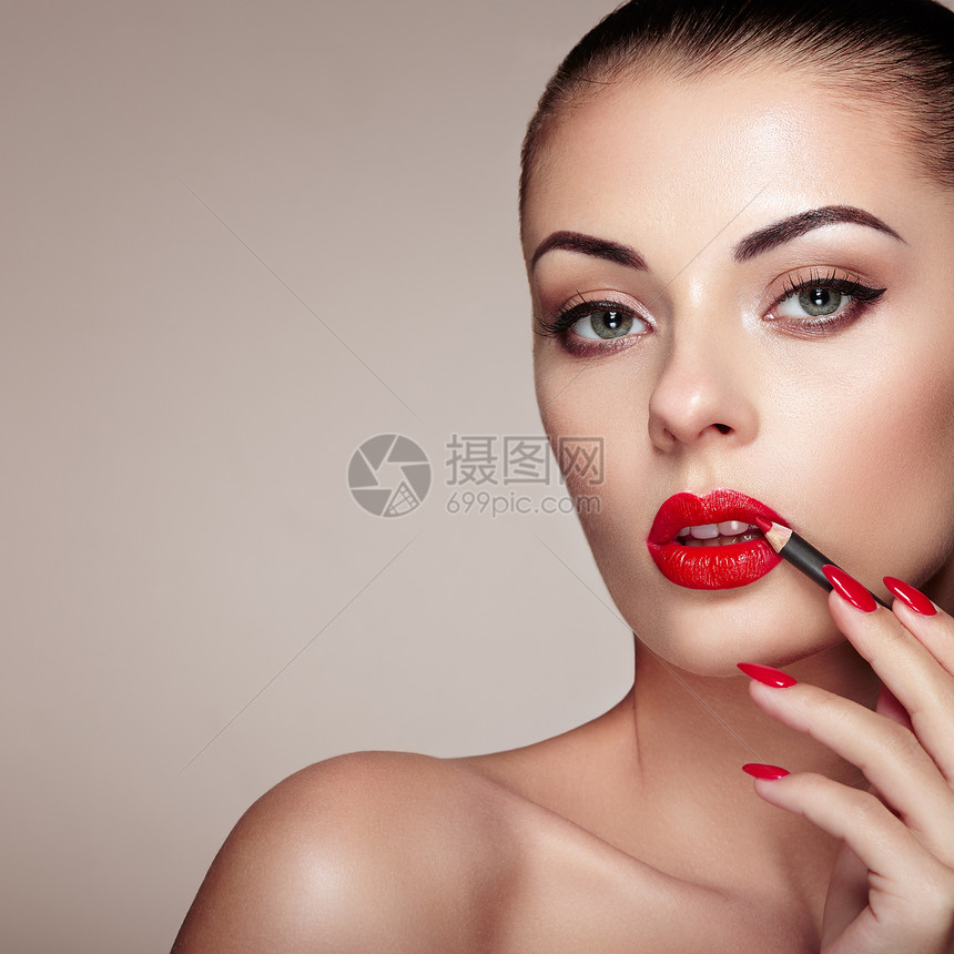 美丽的女人用口红涂嘴唇漂亮的女人脸化妆细节完美皮肤的美容模特红唇指甲修剪图片