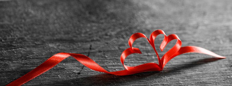 两颗丝带木头上两颗红色丝带的心木制的背,情人节的图片