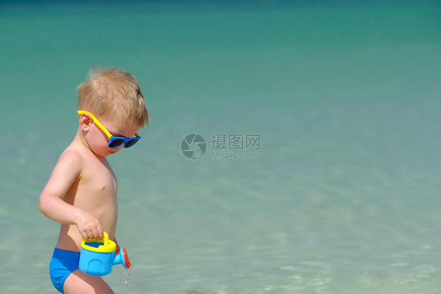 两岁的蹒跚学步的男孩海滩上玩海滩玩具图片