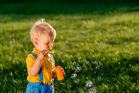 童装特惠小男孩肥皂泡在草地上背景