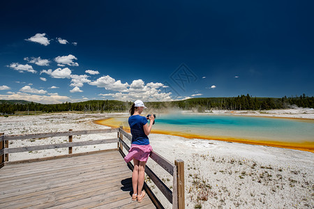 女子游客与相机俯瞰温泉日落湖黄石公园,黑沙盆地地区,怀俄明州,美国图片