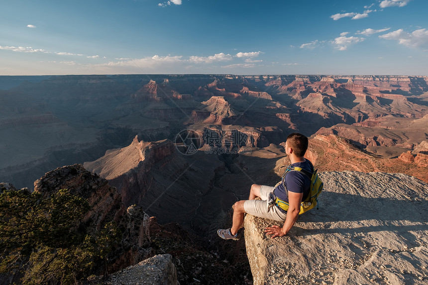 游客与背包大峡谷坐岩石边缘,亚利桑那州,美国图片