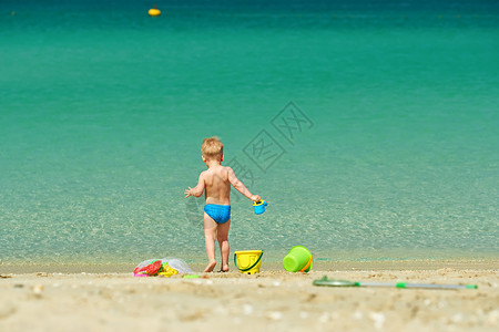两岁的蹒跚学步的男孩海滩上玩海滩玩具高清图片