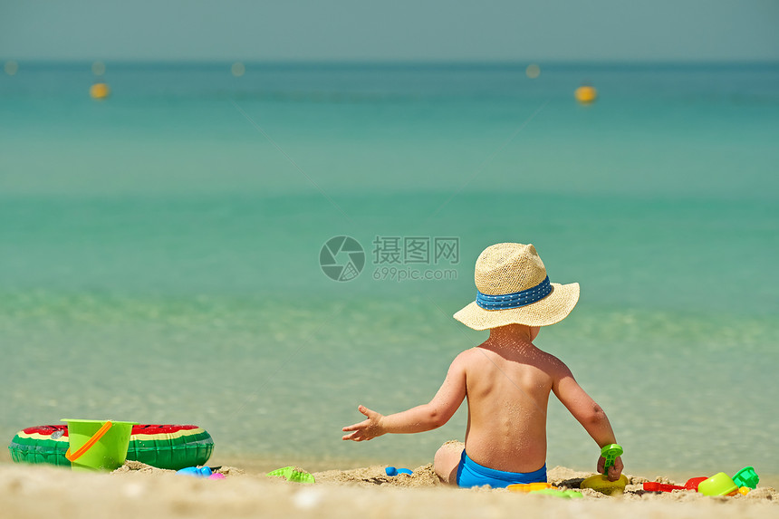 两岁的蹒跚学步的男孩海滩上玩海滩玩具图片
