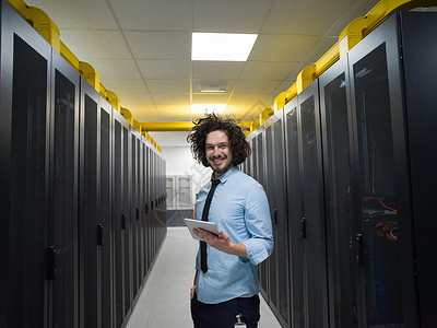 男IT工程师现代数据中心服务器机房的平板电脑上工作图片