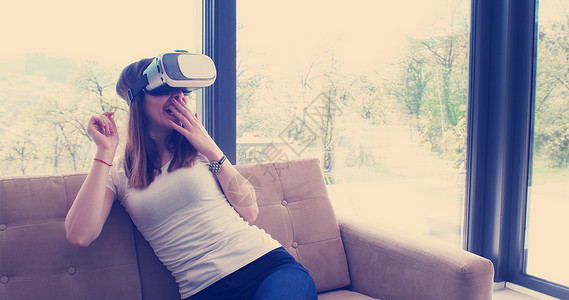微笑快乐的女人获得经验,用虚拟现实的VR耳机眼镜家里图片