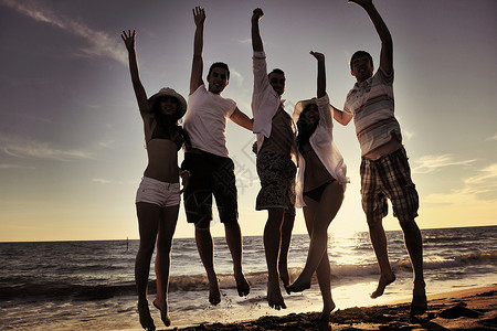 一群年轻朋友们在日落的海滩上跳跃图片素材