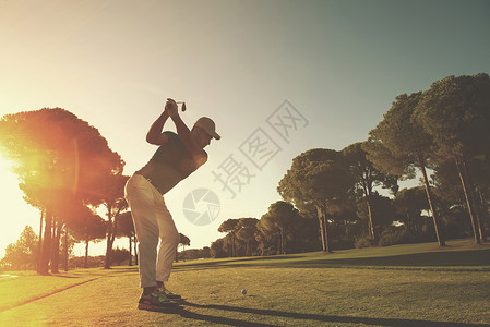 高尔夫球手击球与球杆美丽的早晨与太阳耀斑背景高尔夫球运动员用棍棒击球图片