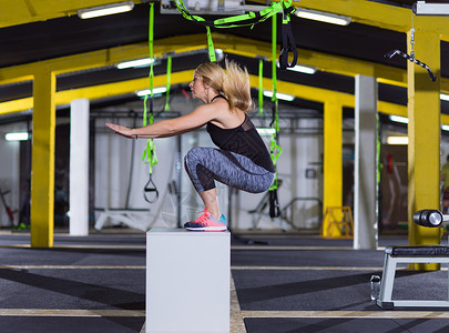 女人健身箱上跳出来轻的运动女子训练跳跃健身箱交叉健身健身房图片