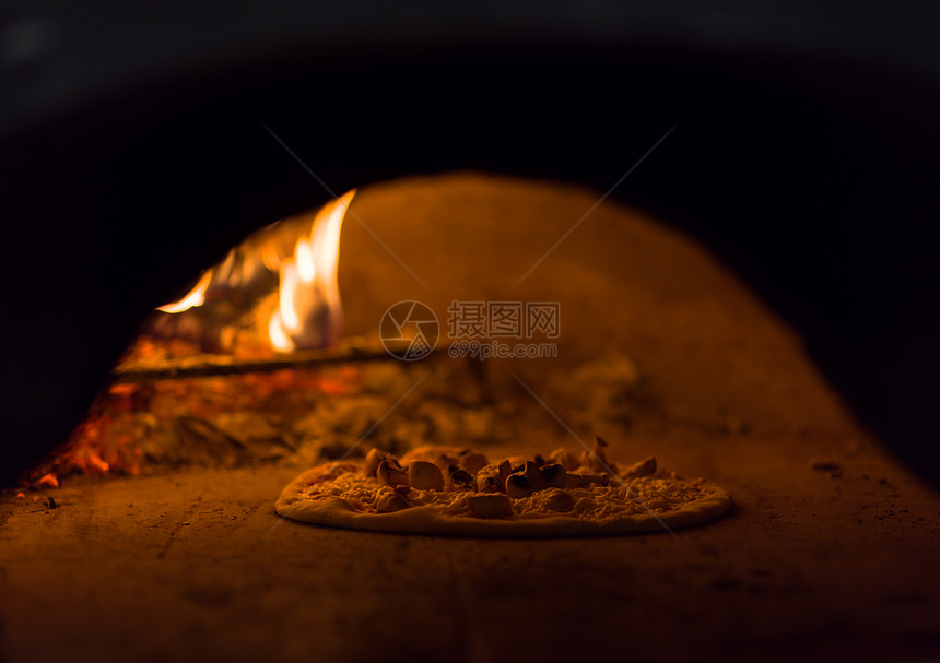 厨师用木柴火焰把美味的比萨饼放砖木烤箱里厨师把美味的比萨饼放砖木烤箱里图片