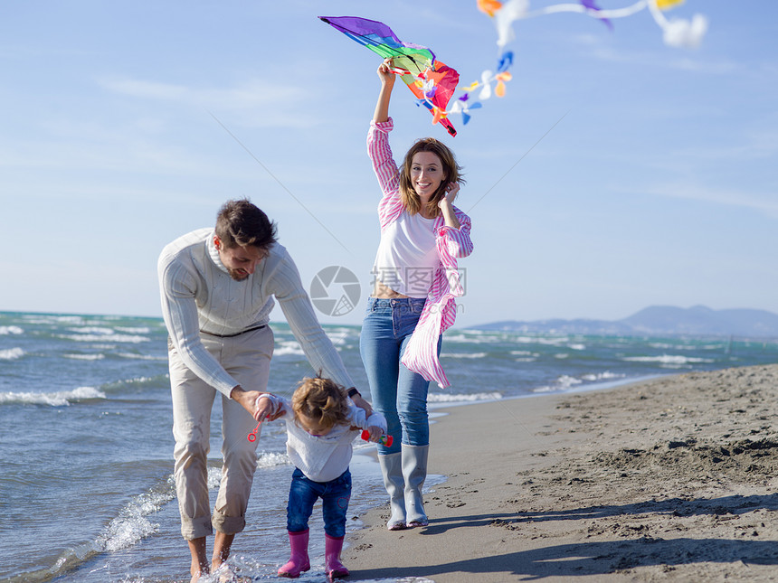 家庭与小女儿休息玩风筝海滩秋天的天快乐的家庭秋天享受祝福图片