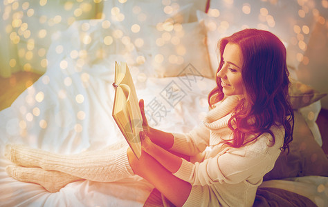 舒适休闲人的快乐的轻女家里卧室的床上看书快乐的轻女人家床上看书图片