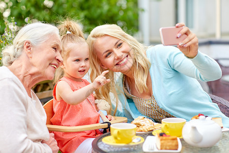 祖母照片素材家庭世代人的快乐的母亲女儿祖母咖啡馆餐厅露台用智能手机自拍幸福的家庭咖啡馆自拍背景