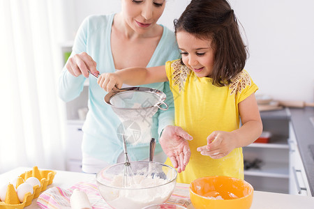 家庭,烹饪,烘焙人们的快乐的母亲小女儿用筛子筛粉家里厨房快乐的母女家烘焙图片
